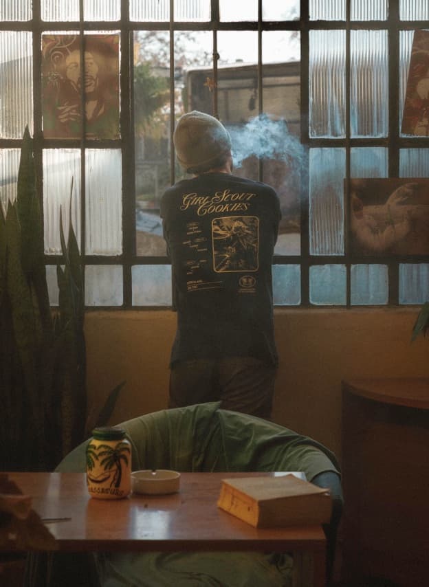 Persona de espaldas fumando junto a una ventana enrejada, en el interior de un club